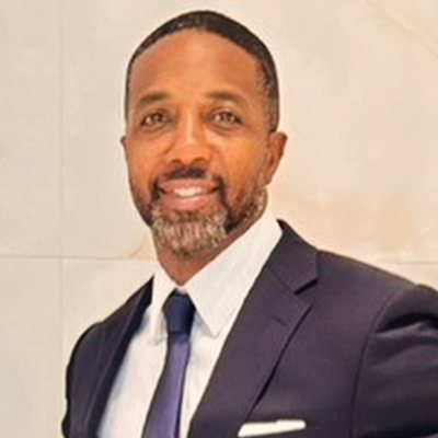Mike Rumph smiling in a navy suit, white shirt and blue tie